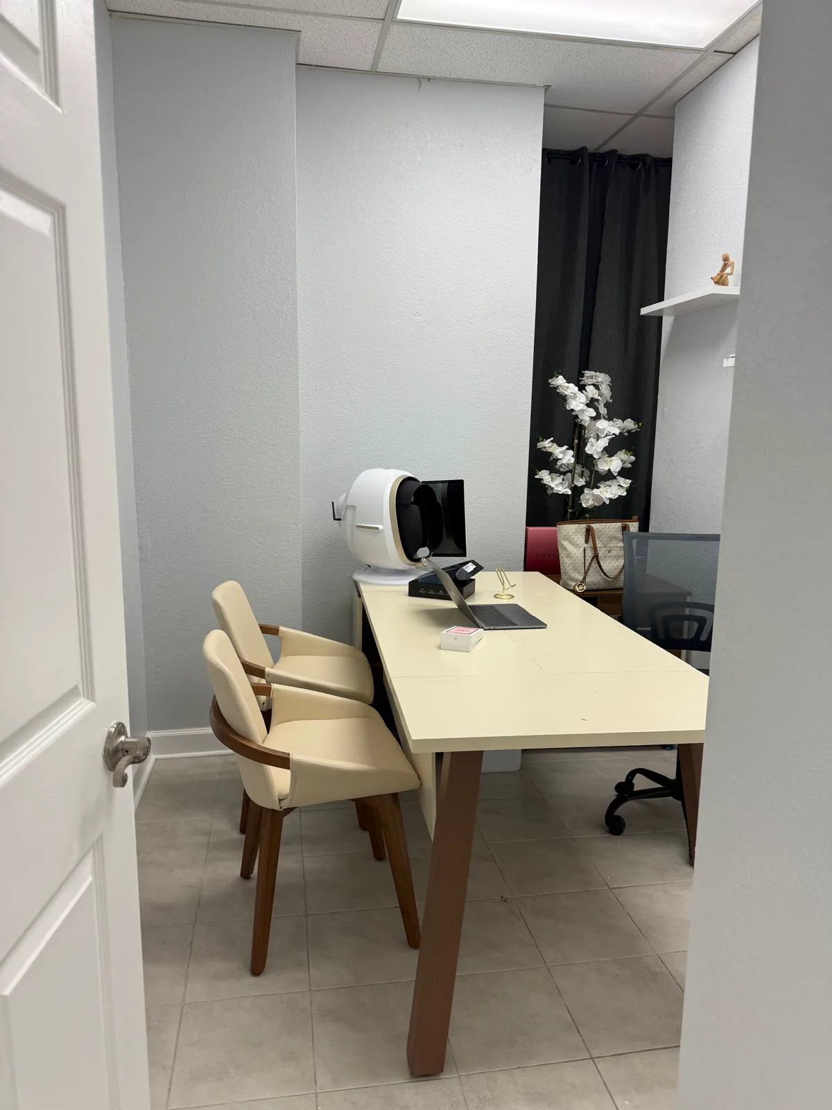 Consultation room with digital skin diagnosis equipment, white orchids, and cream chairs
