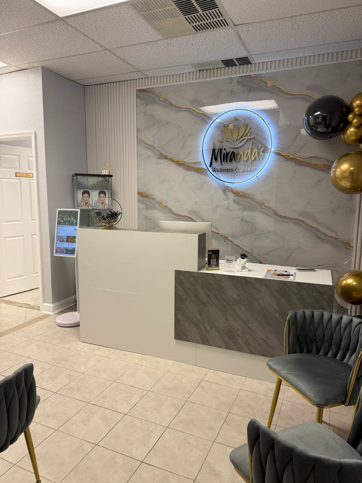 Reception lobby with marble wall, illuminated Miranda's logo, and gold accents